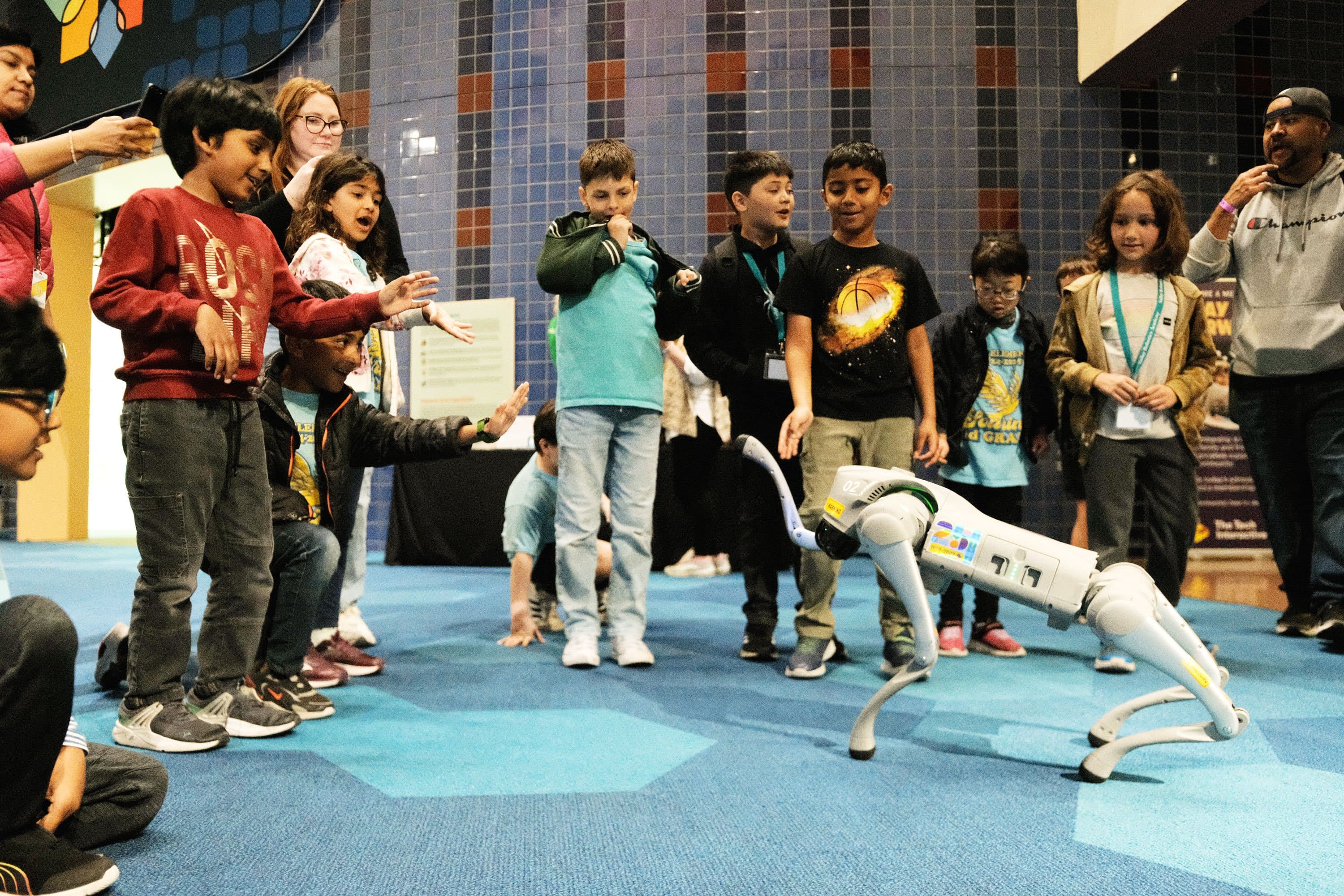 A group of school students interacting with a robotic dog. 